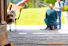Ein Hund schaut vor einer Tür hervor, im Hintergrund zwei Personen