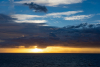 Blick aufs Meer, die aufgehende Sonne ist hinter einem Wolkenband versteckt